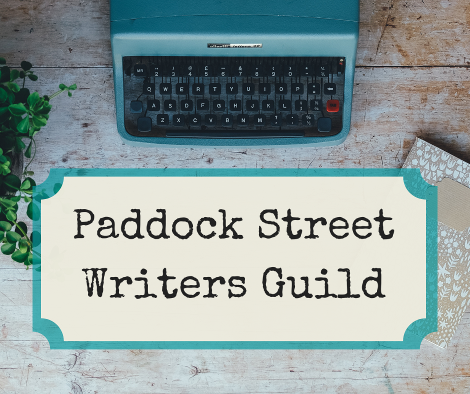 Paddock Street Writers Guild Logo beneath a teal typewriter on a wooden table