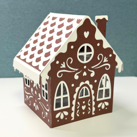Brown cardstock gingerbread house with white decorative details 