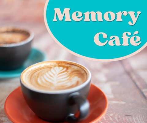 two lattes in black mugs on a wooded table beneath the Memory Cafe Logo