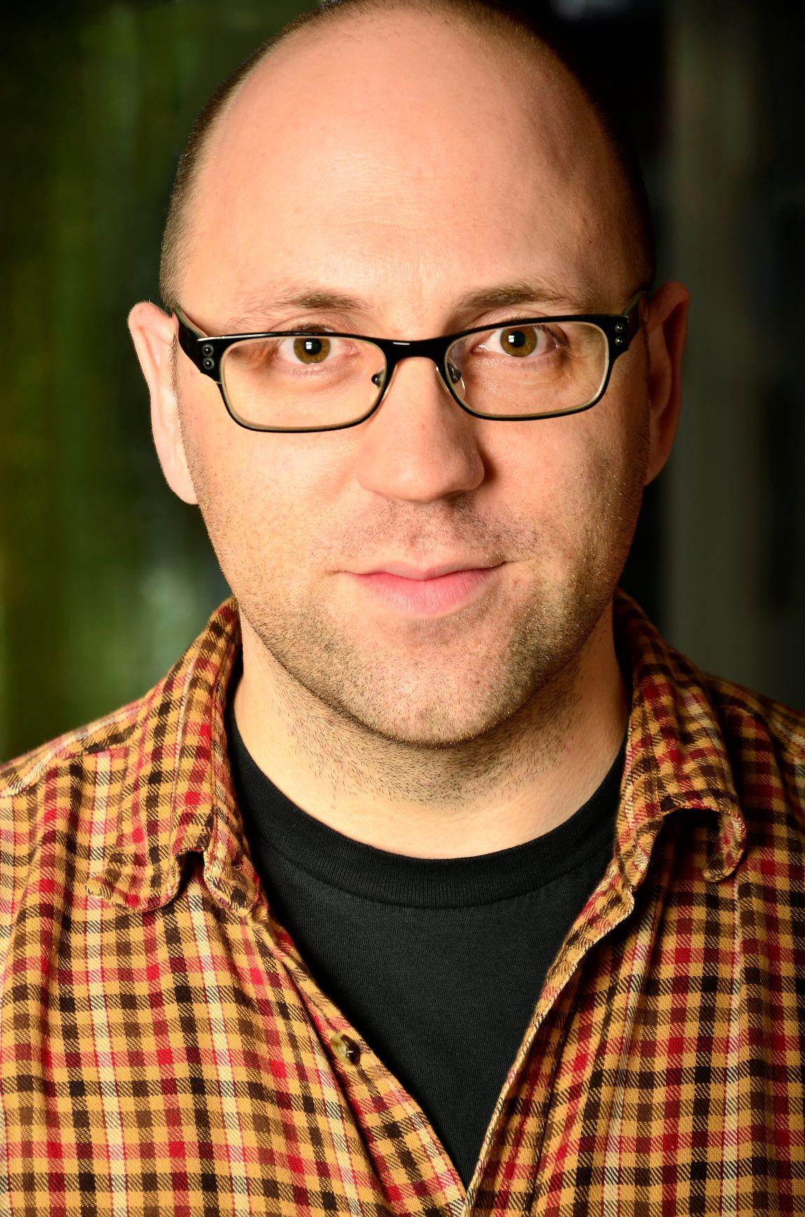 Photo of author Daniel Kraus, a Caucasian man with glasses, a shaved head, and light goatee